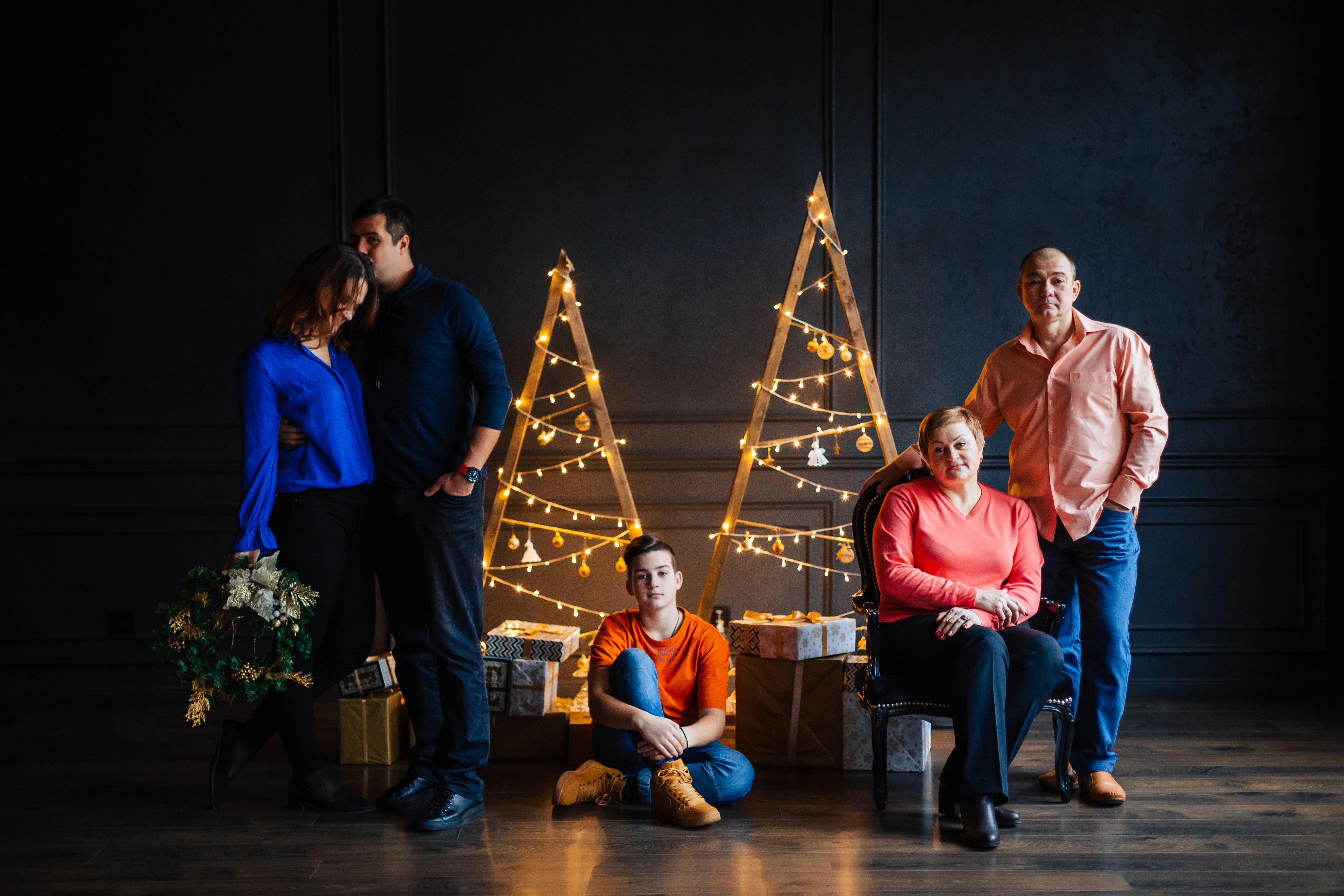 A group of people standing and sitting in front of a christmas tree ...