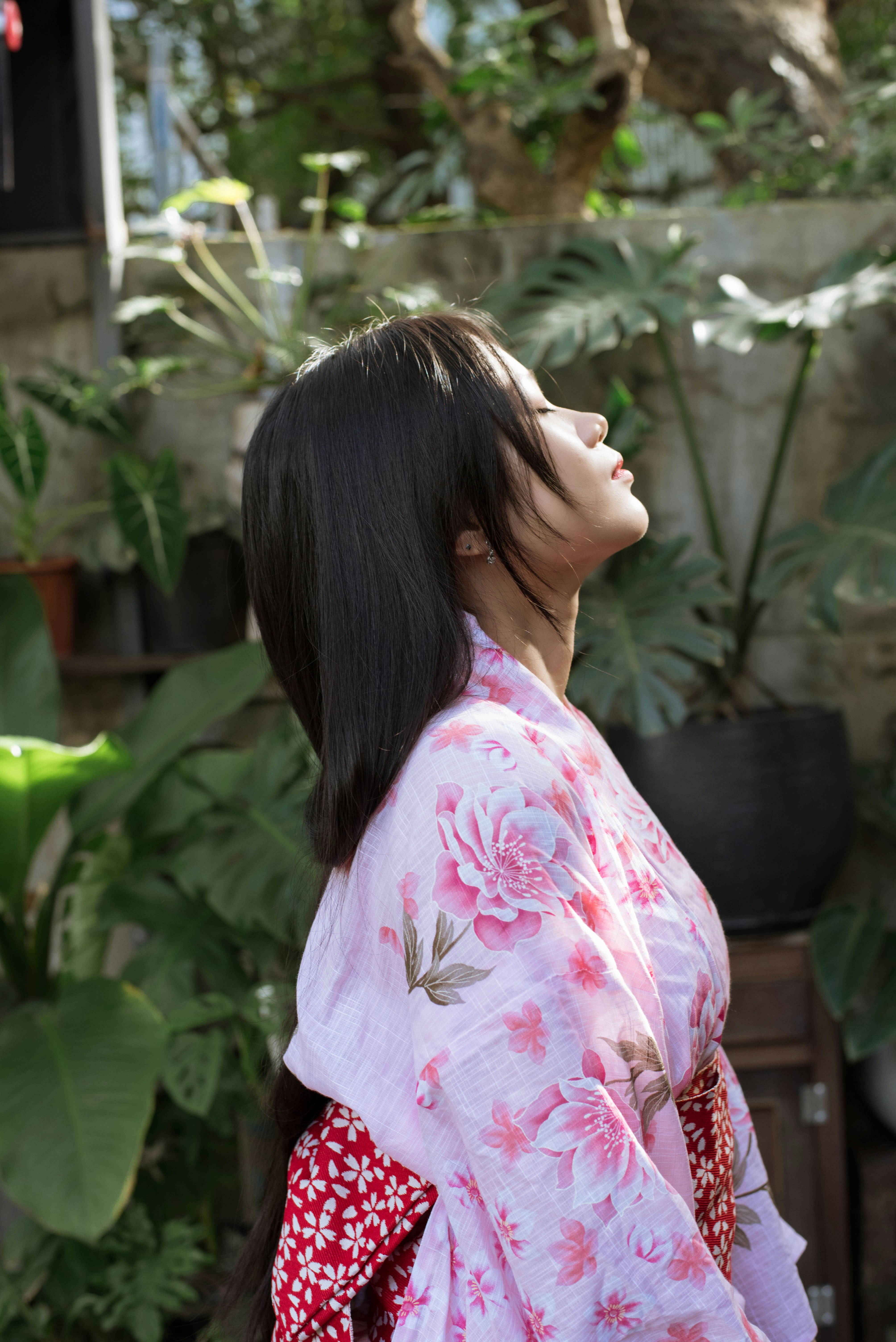 Una mujer con un kimono parada frente a unas plantas