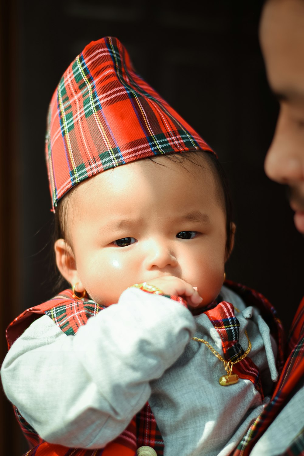 a man holding a baby wearing a plaid hat