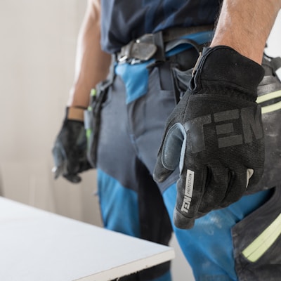 a man wearing a pair of black and blue work gloves