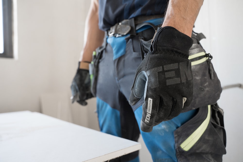 a man wearing a pair of black and blue work gloves