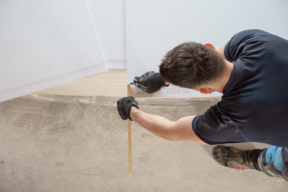 a man measuring a piece of wood with a measuring tape