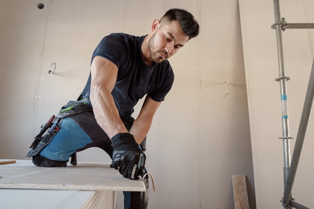 a man in black shirt working on a piece of wood