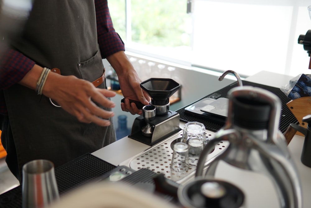a person standing in a kitchen preparing a cup of coffee