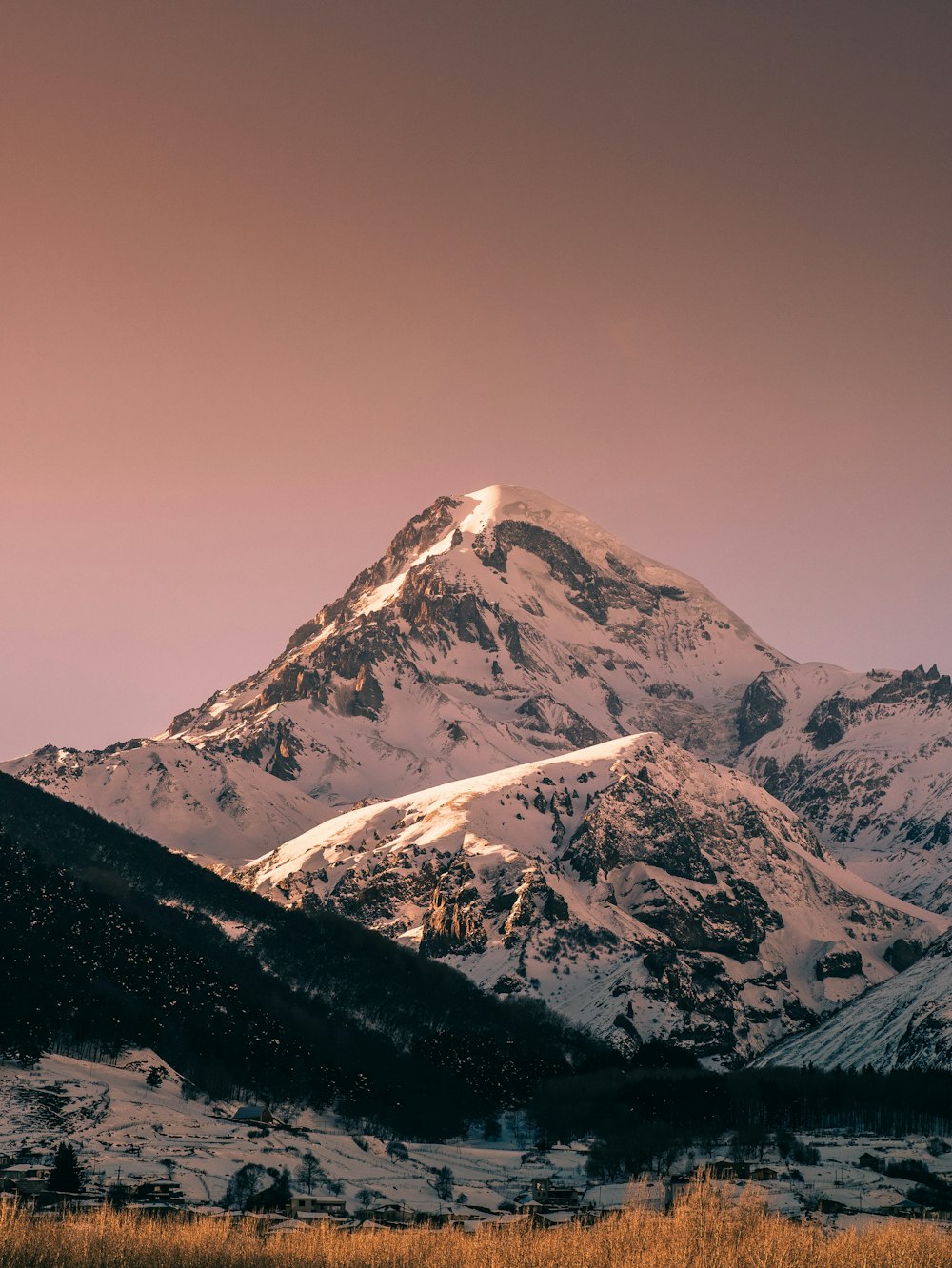 a snow covered mountain with a pink sky in the background