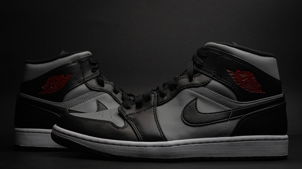 a pair of black and grey sneakers on a black background