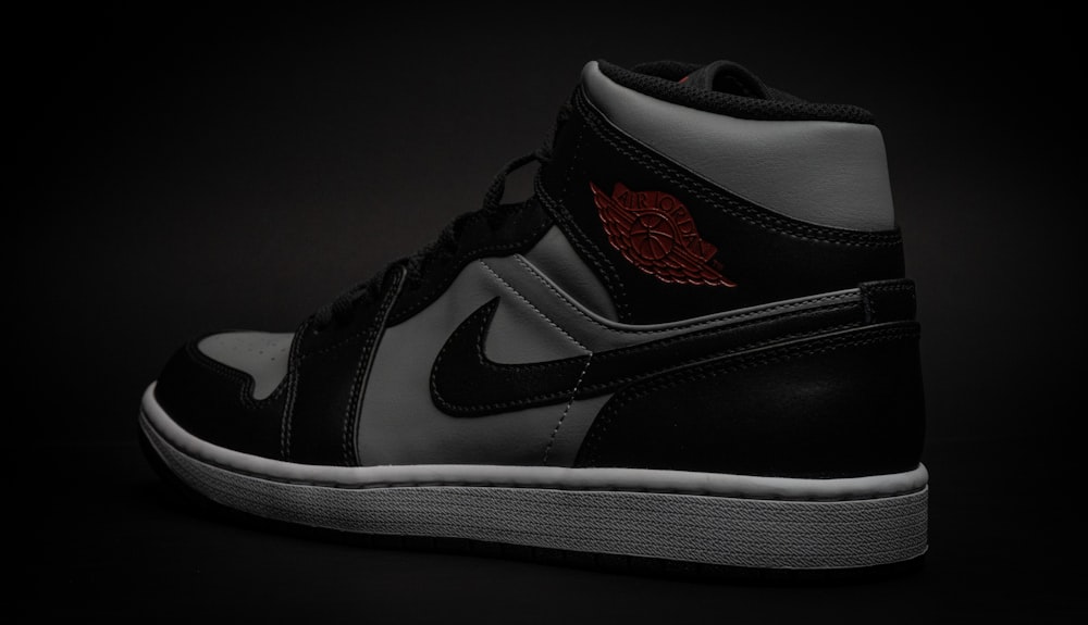a pair of black and white sneakers on a black background