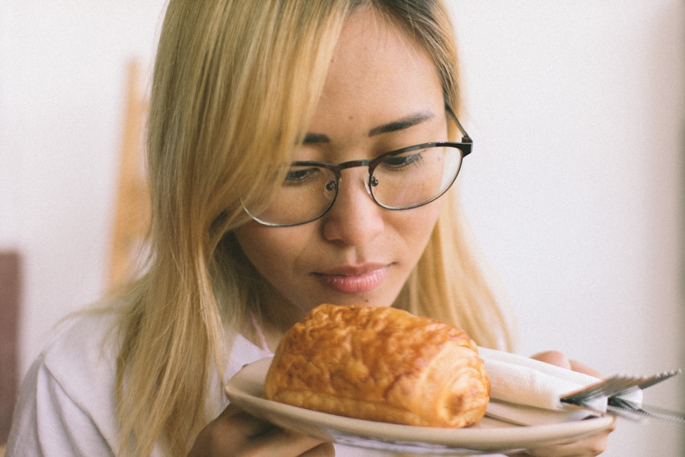 a woman holding a plate with a croissant on it