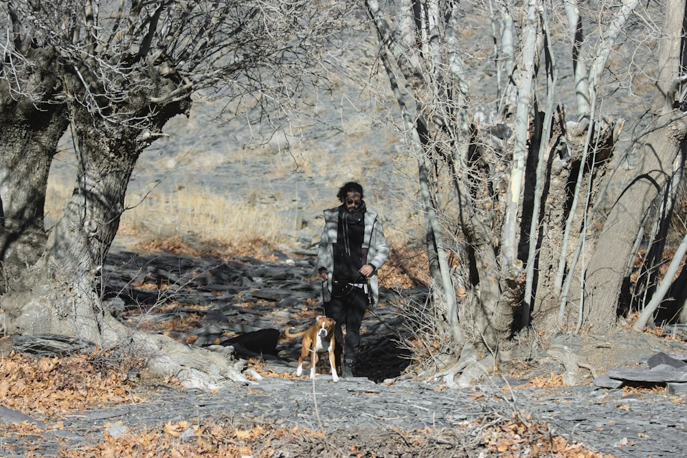 a man walking a dog through a forest