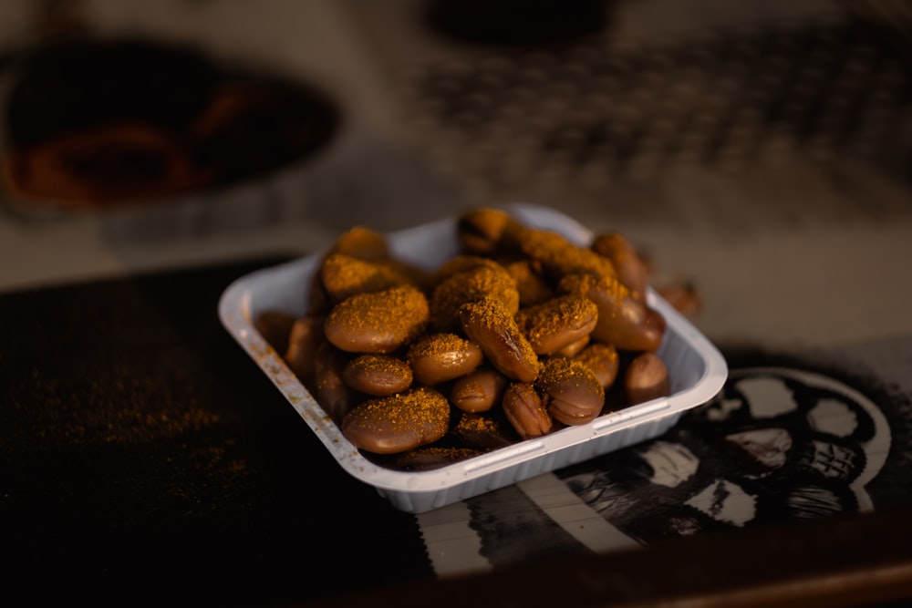 un tazón de cacahuetes sentado encima de una mesa