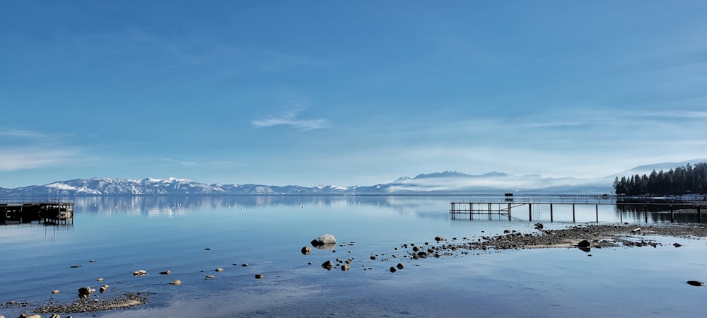 a body of water with a dock and mountains in the background