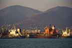 a large cargo ship in a harbor with mountains in the background