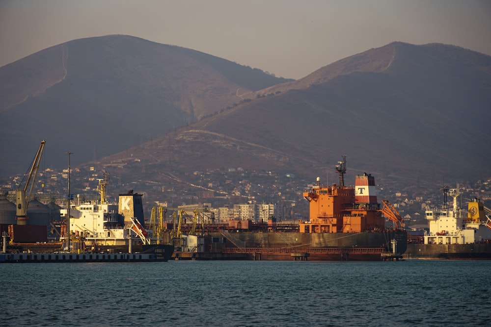 a large cargo ship in a harbor with mountains in the background