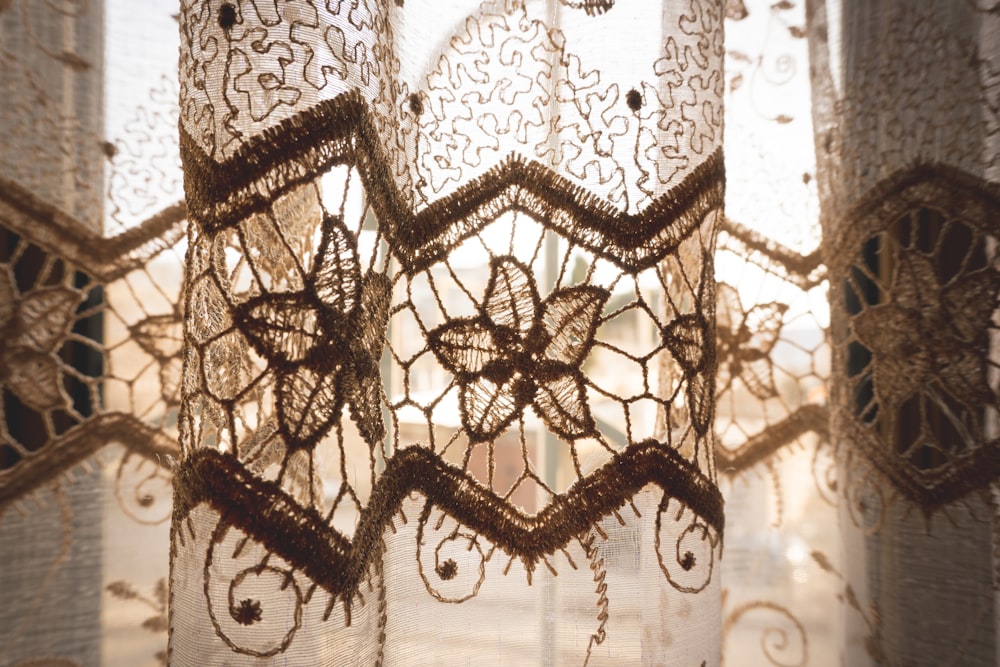 a close up of a lace curtain with a window in the background