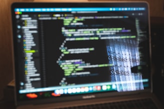 Abstract neon gradient shapes surrounding a laptop showing code updates on screen.