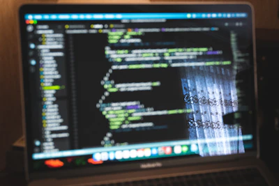 Close-up of a laptop screen showing AI code with traditional Moroccan patterns in the background.