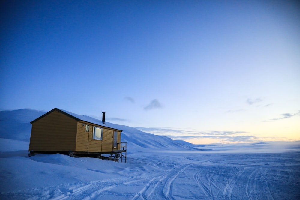 a small cabin sitting on top of a snow covered slope