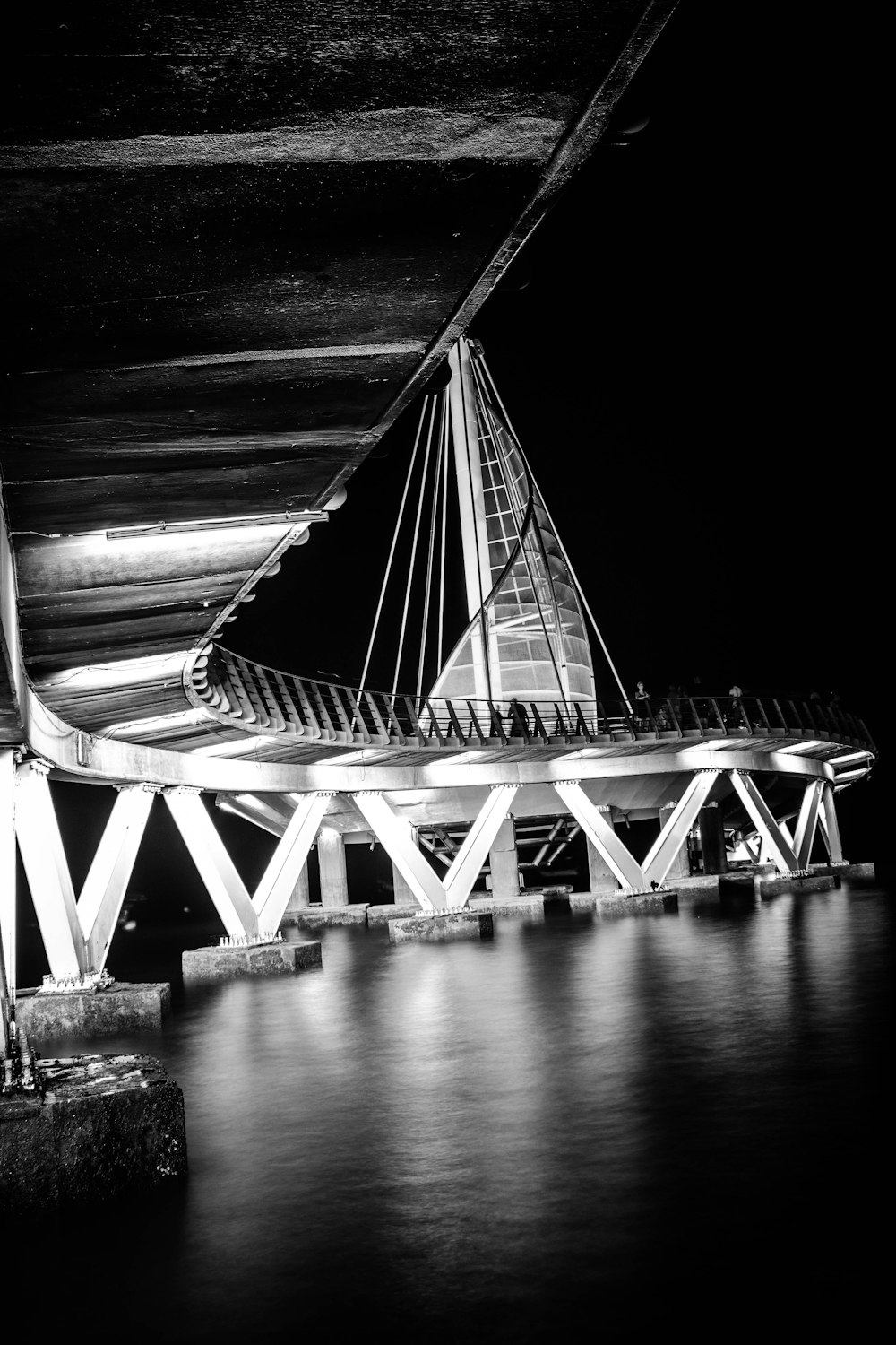 a black and white photo of a bridge at night