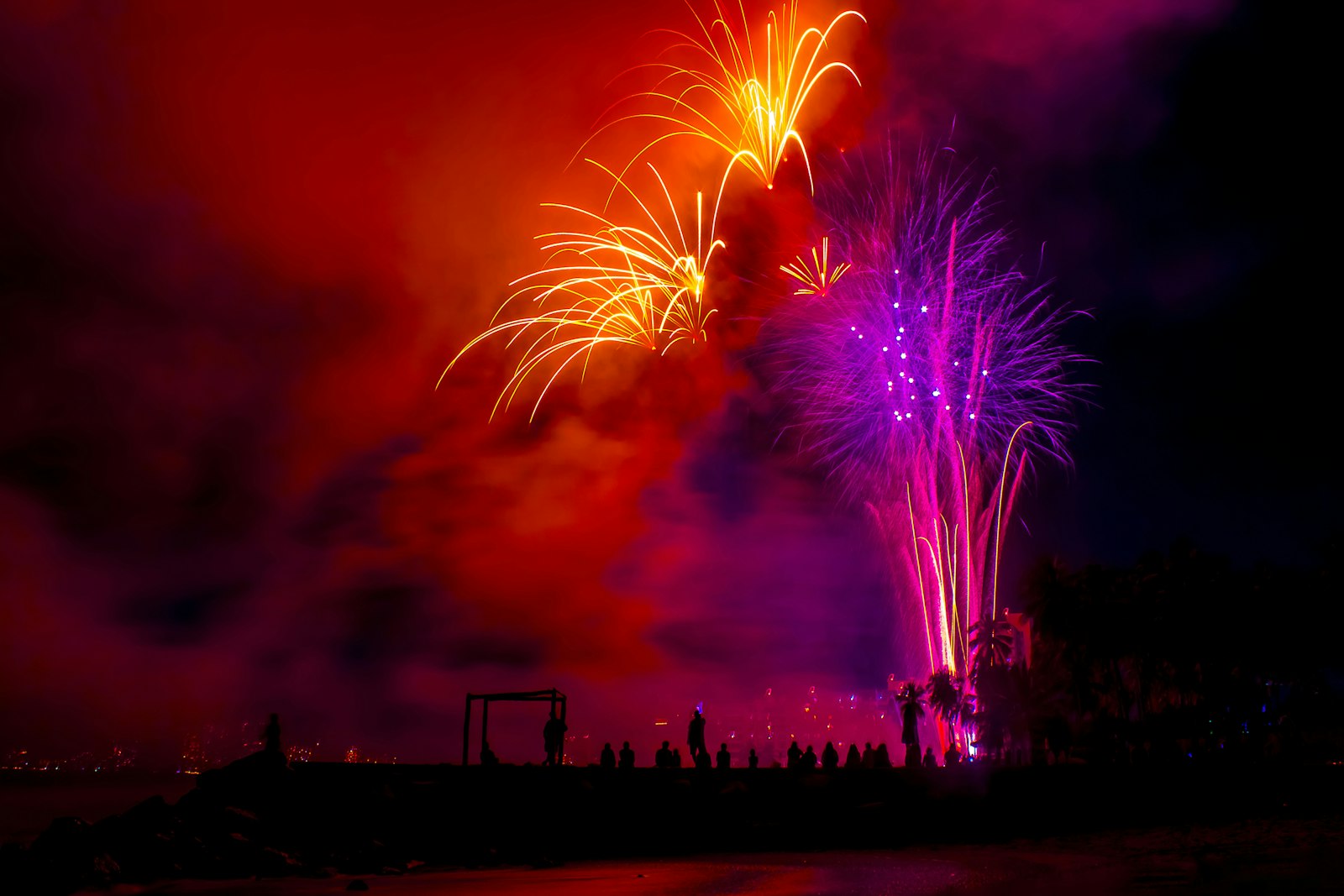Feux d'artifice rouges et violets au-dessus du rivage la nuit, comme ceux qui clôturent le Nouvel An à Puerto Vallarta