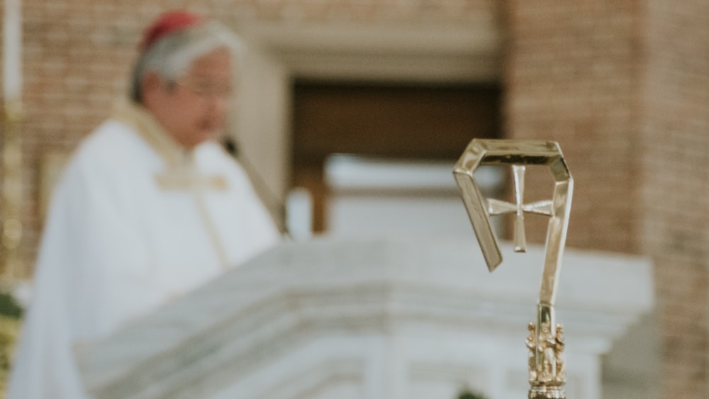 a priest standing in front of a cross