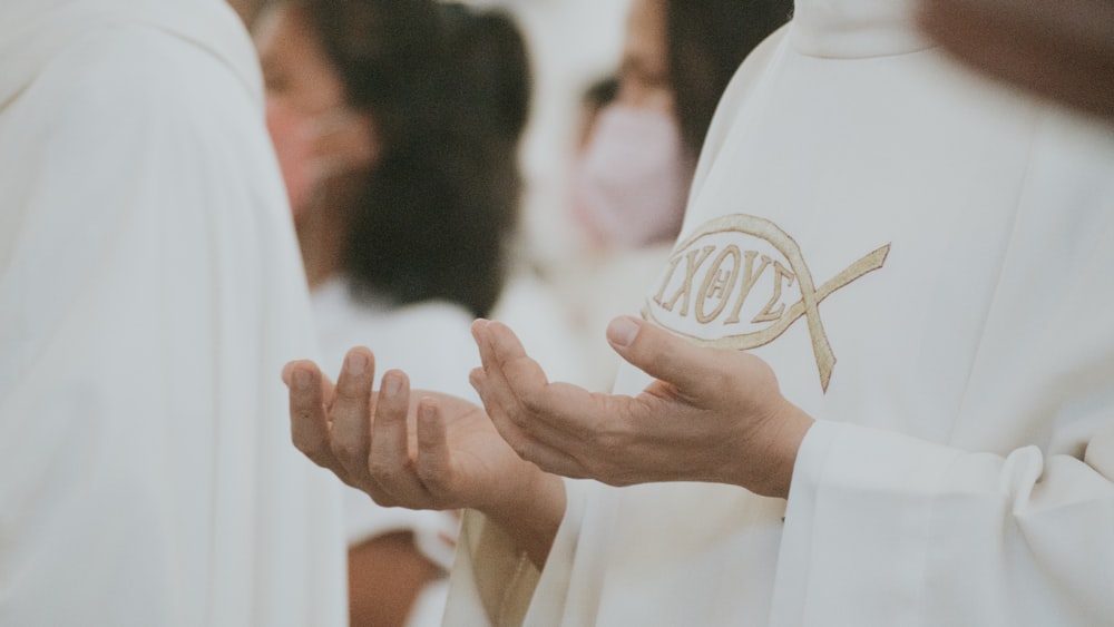 a group of people standing around each other wearing white robes