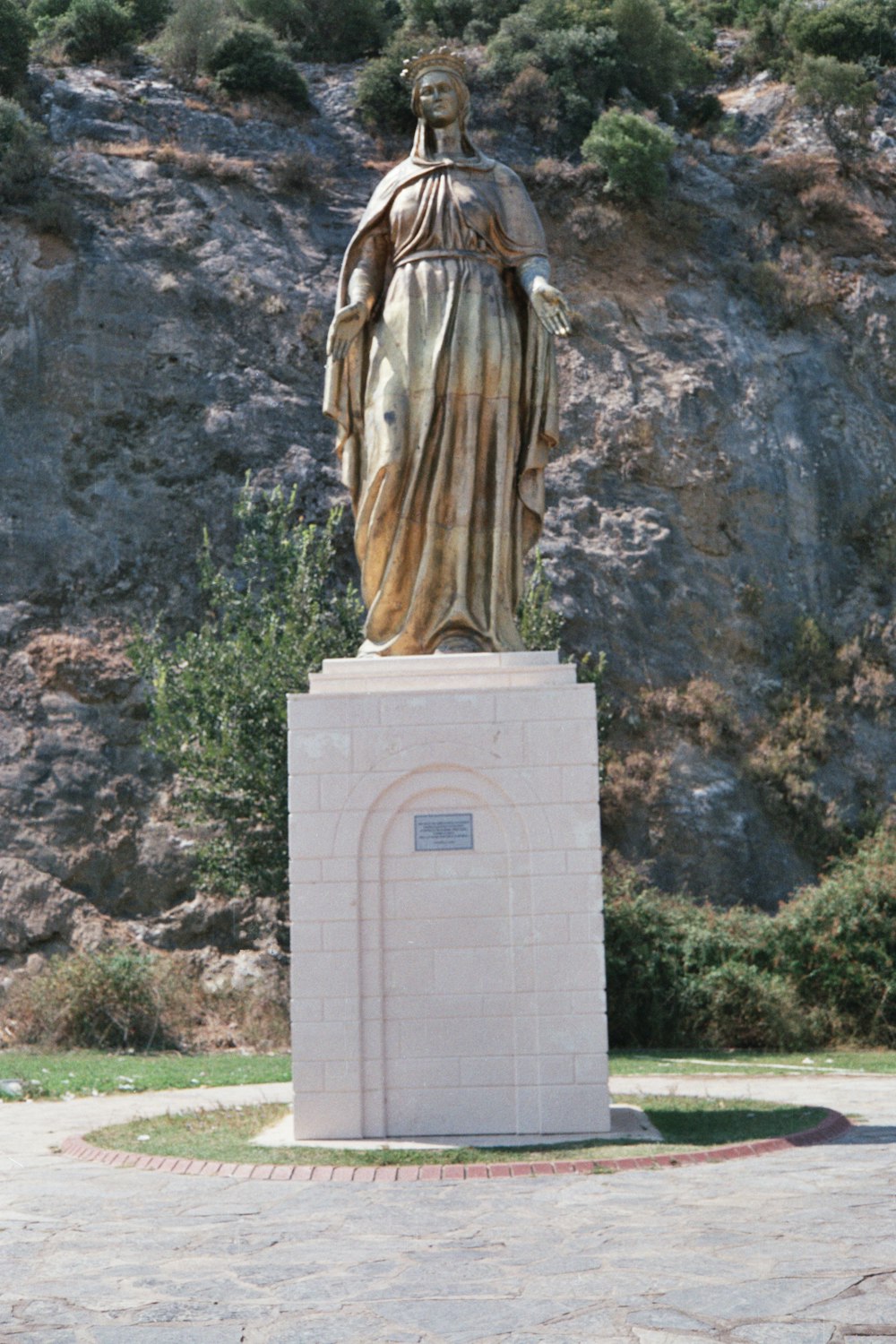 a statue of a woman standing in front of a mountain
