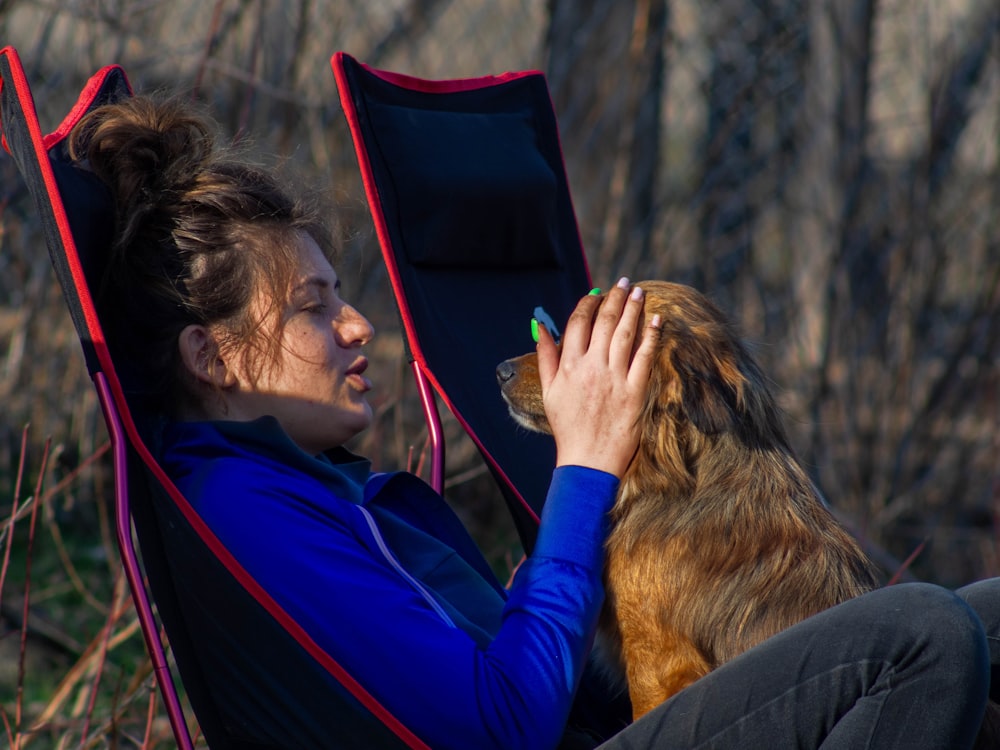 a woman sitting in a chair with her dog