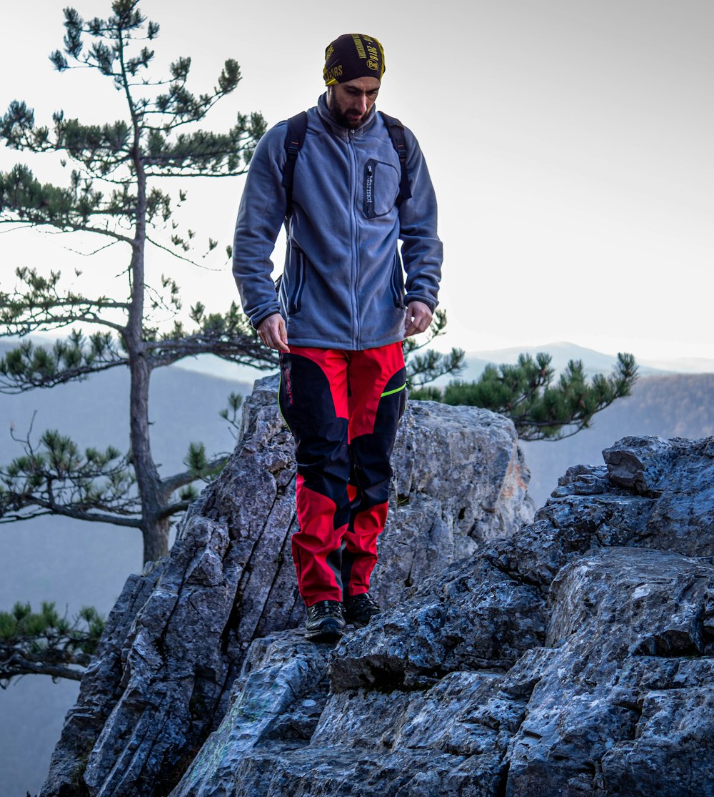 a man standing on top of a mountain next to a tree