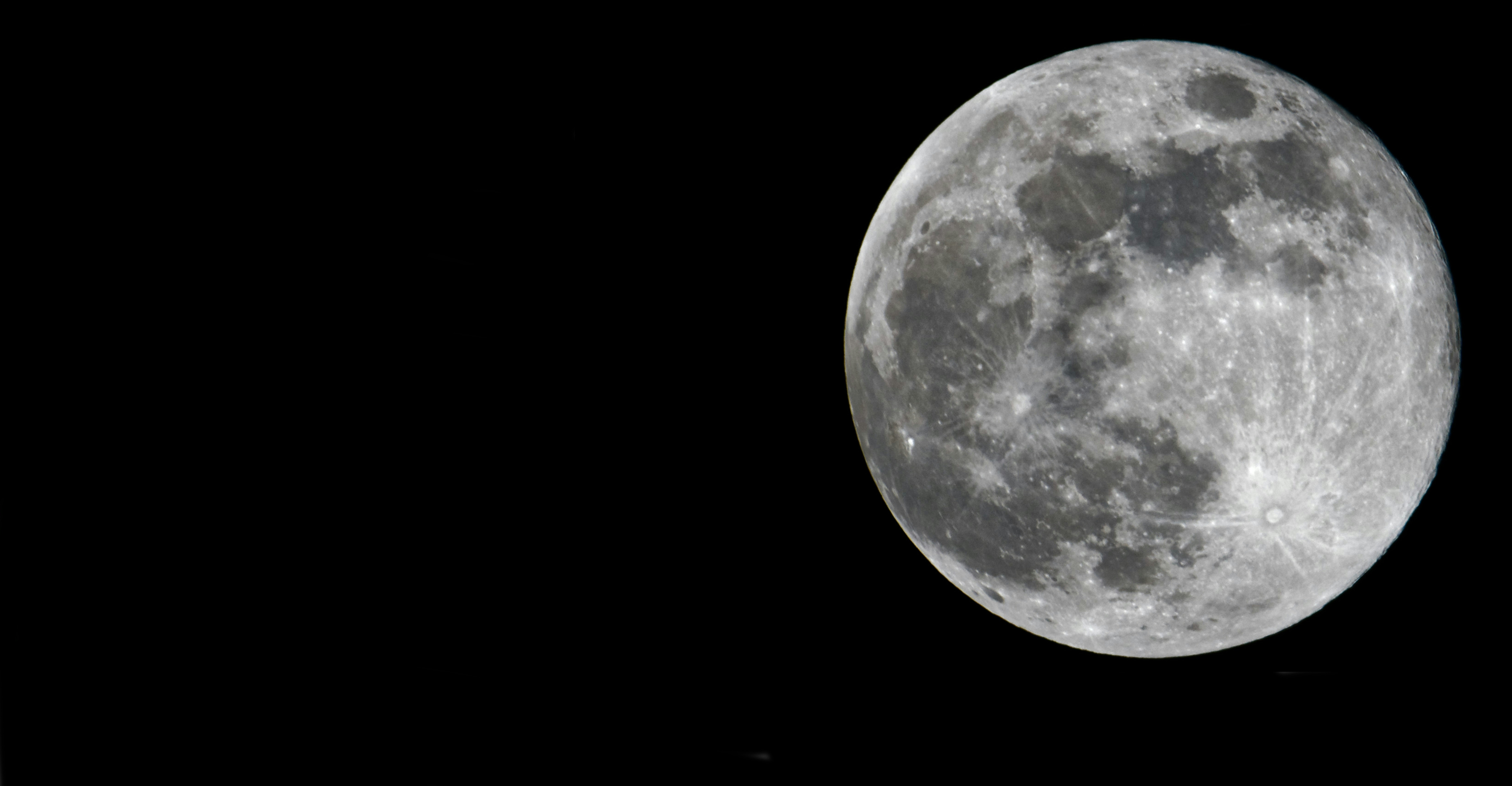 a full moon is seen in the dark sky