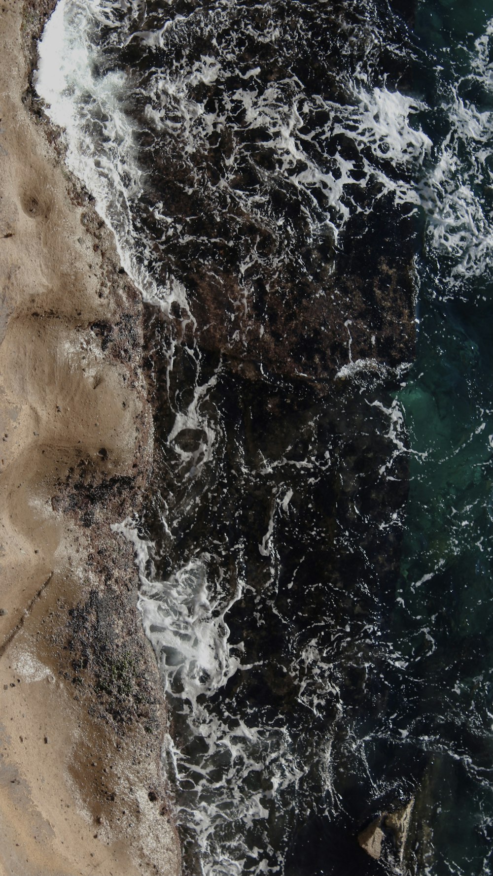 an aerial view of a beach with waves crashing on the shore