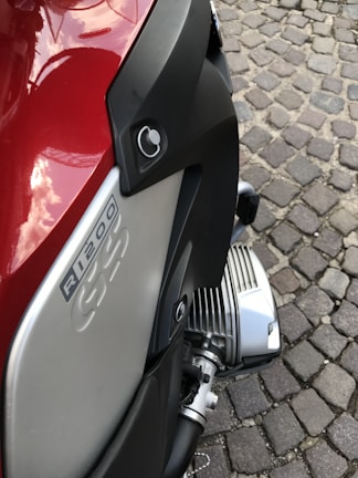 Close-up of a BMW GS parked beside a desert trail, dust swirling around its tires.