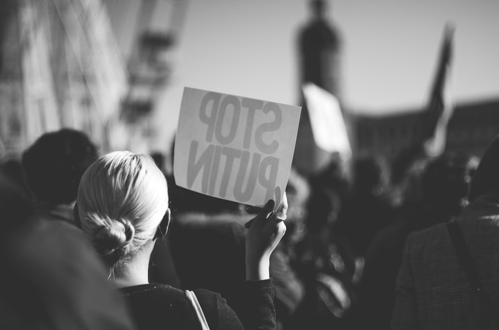 a woman holding a sign that reads stop puttin