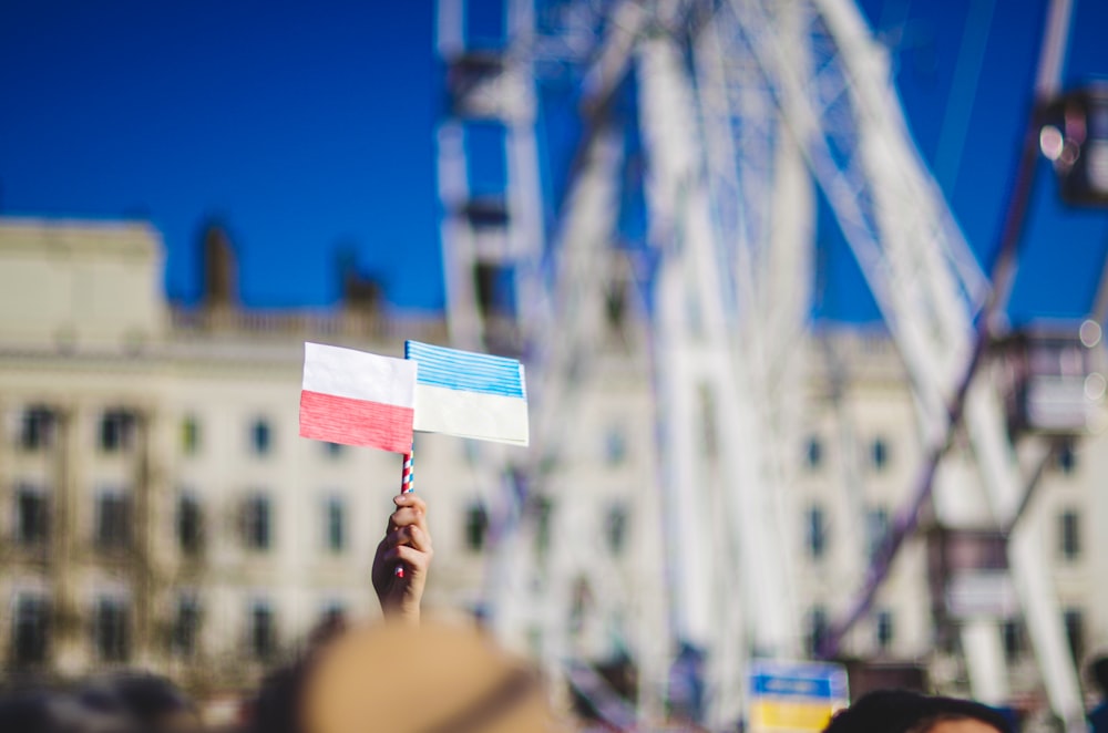 a person holding a flag in front of a ferris wheel