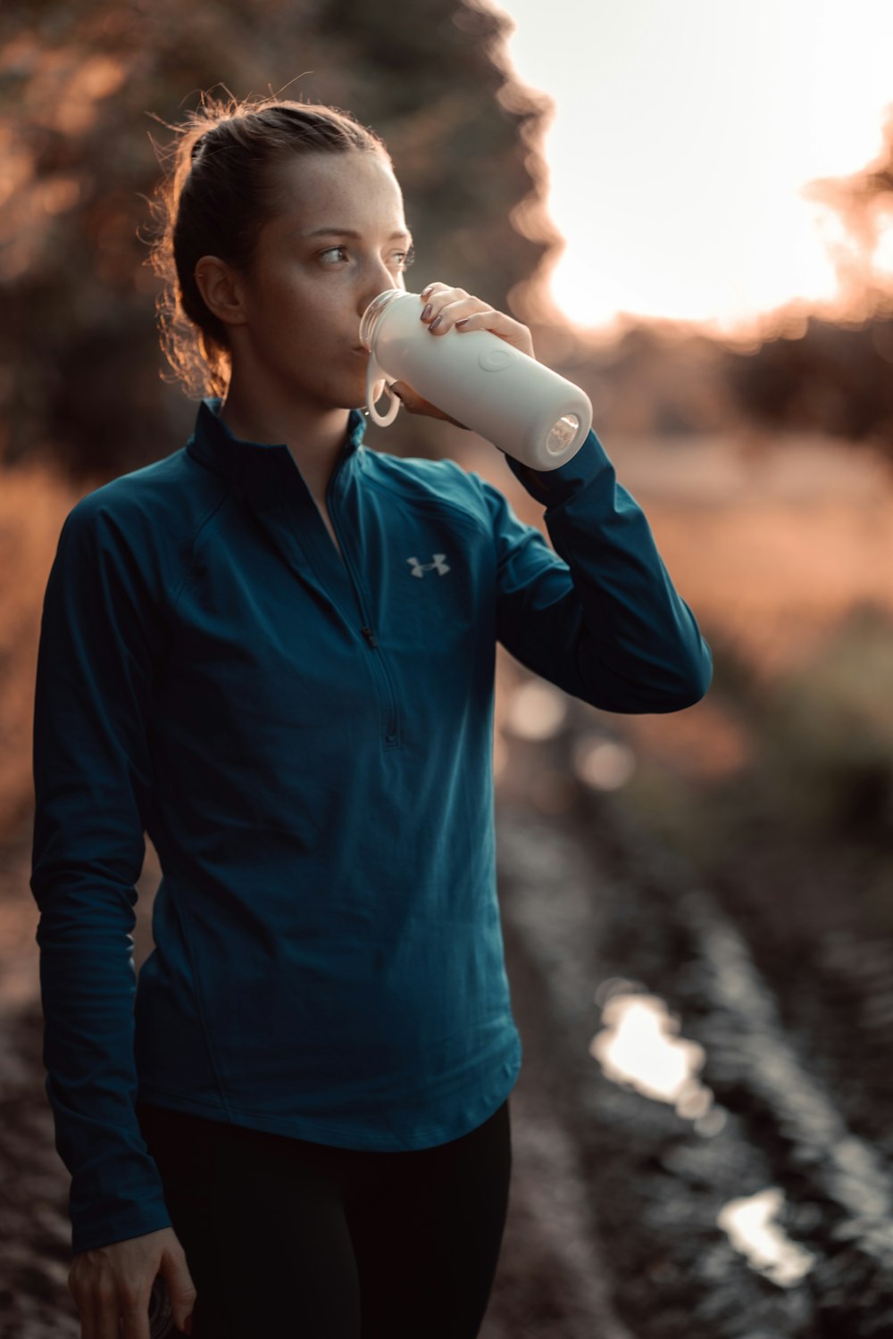 a woman is drinking from a water bottle