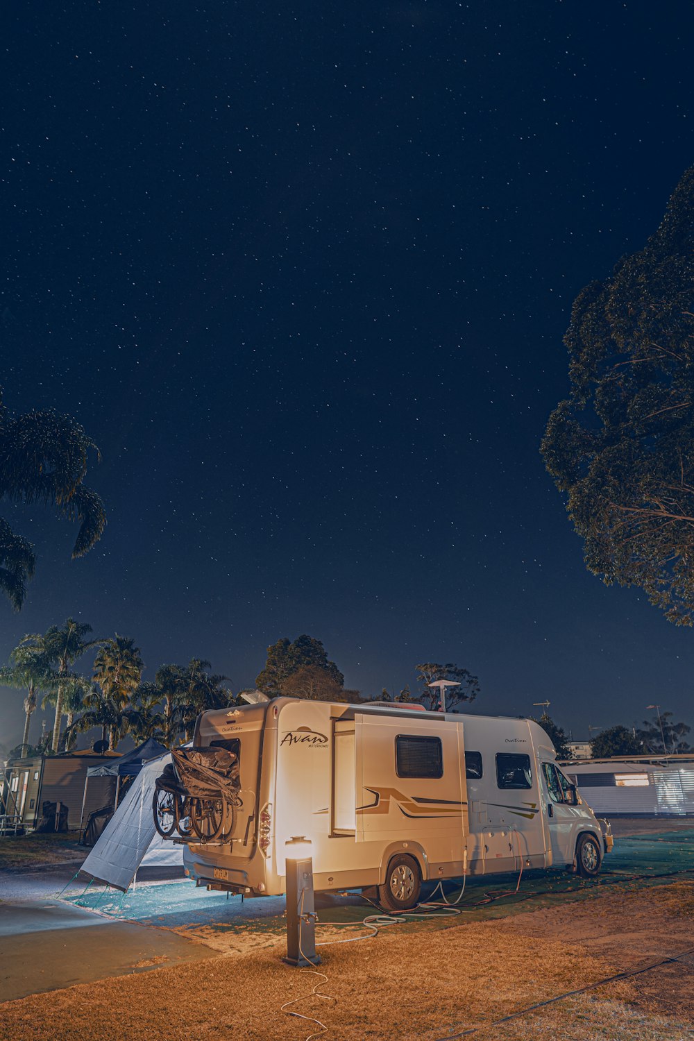 a camper parked next to a tree at night