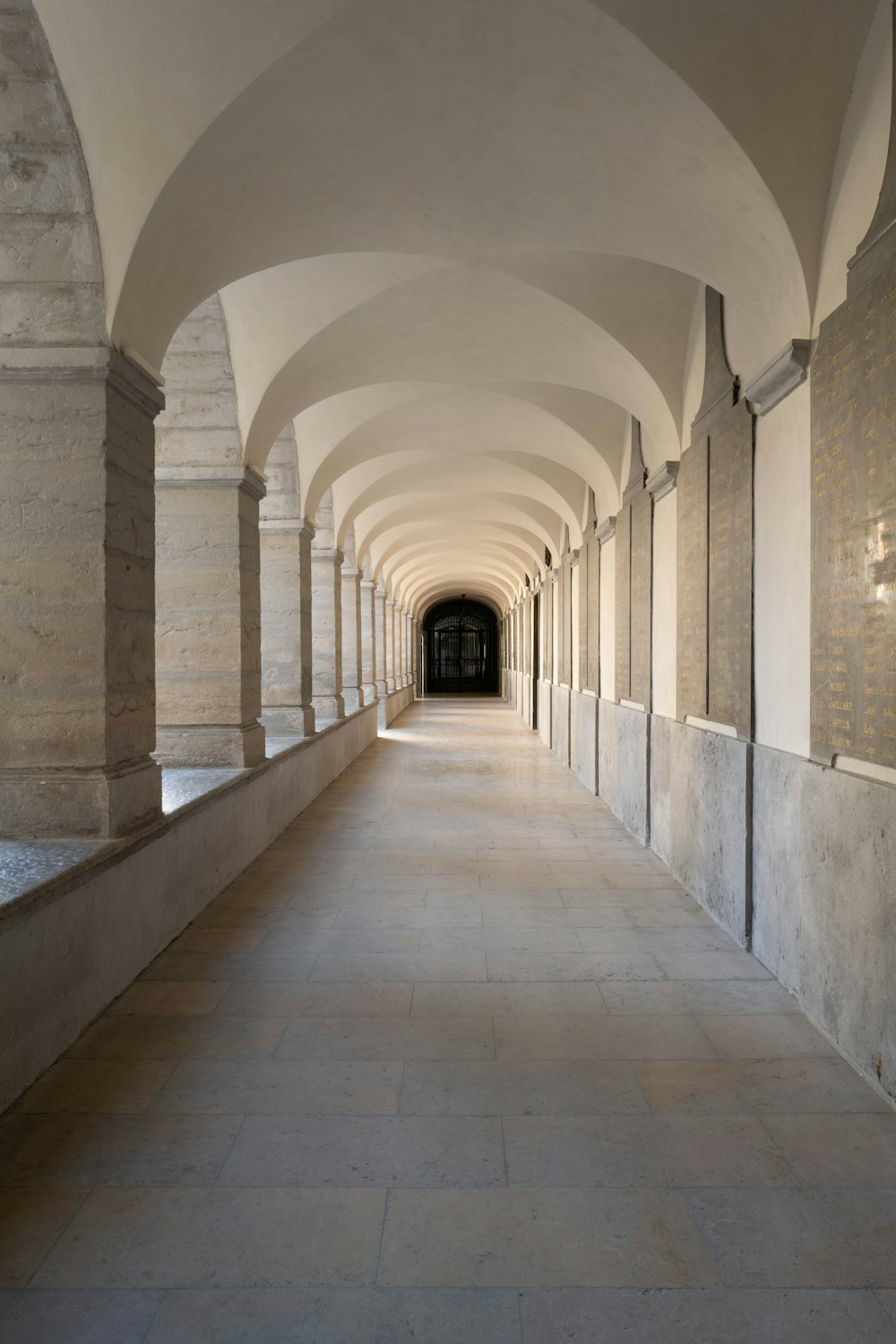 a long hallway with arches and a light at the end