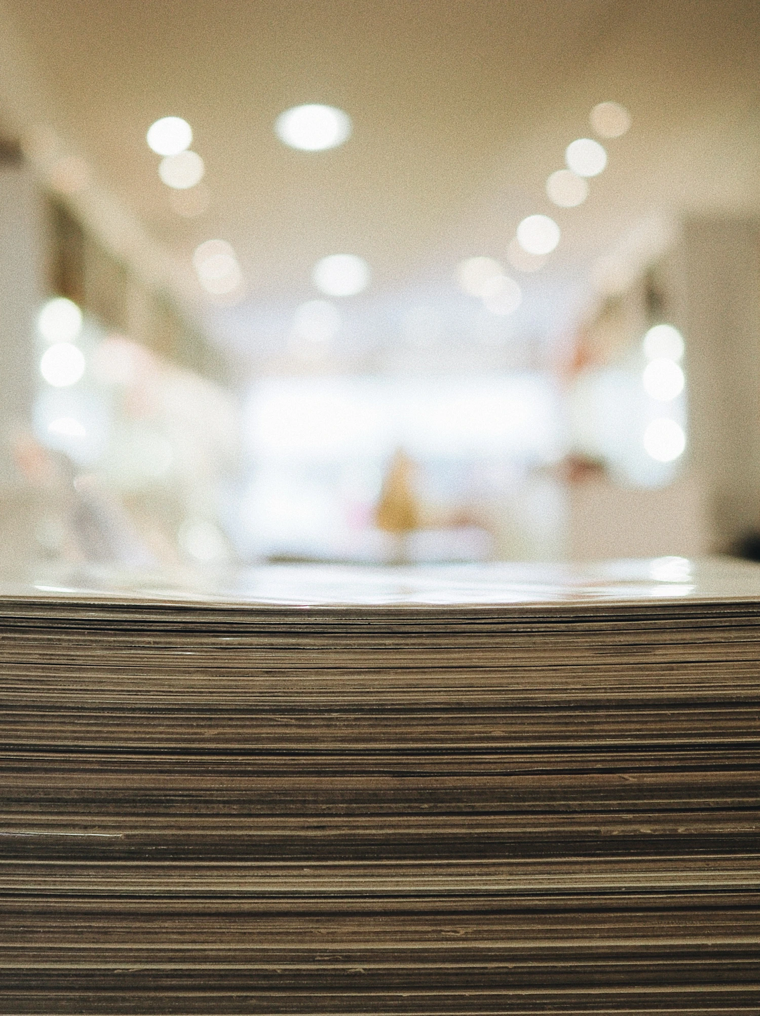 A thick stack of brown paper seen edge-on, the room behind it thrown out of focus
