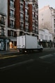 a delivery truck driving down a street next to tall buildings