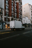 a delivery truck driving down a street next to tall buildings