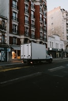 a delivery truck driving down a street next to tall buildings