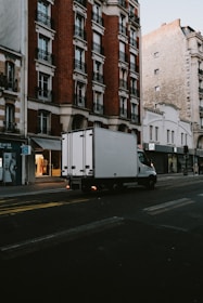 a delivery truck driving down a street next to tall buildings