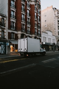 a delivery truck driving down a street next to tall buildings