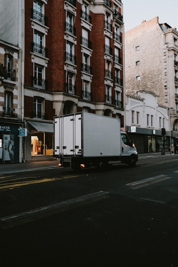 a delivery truck driving down a street next to tall buildings