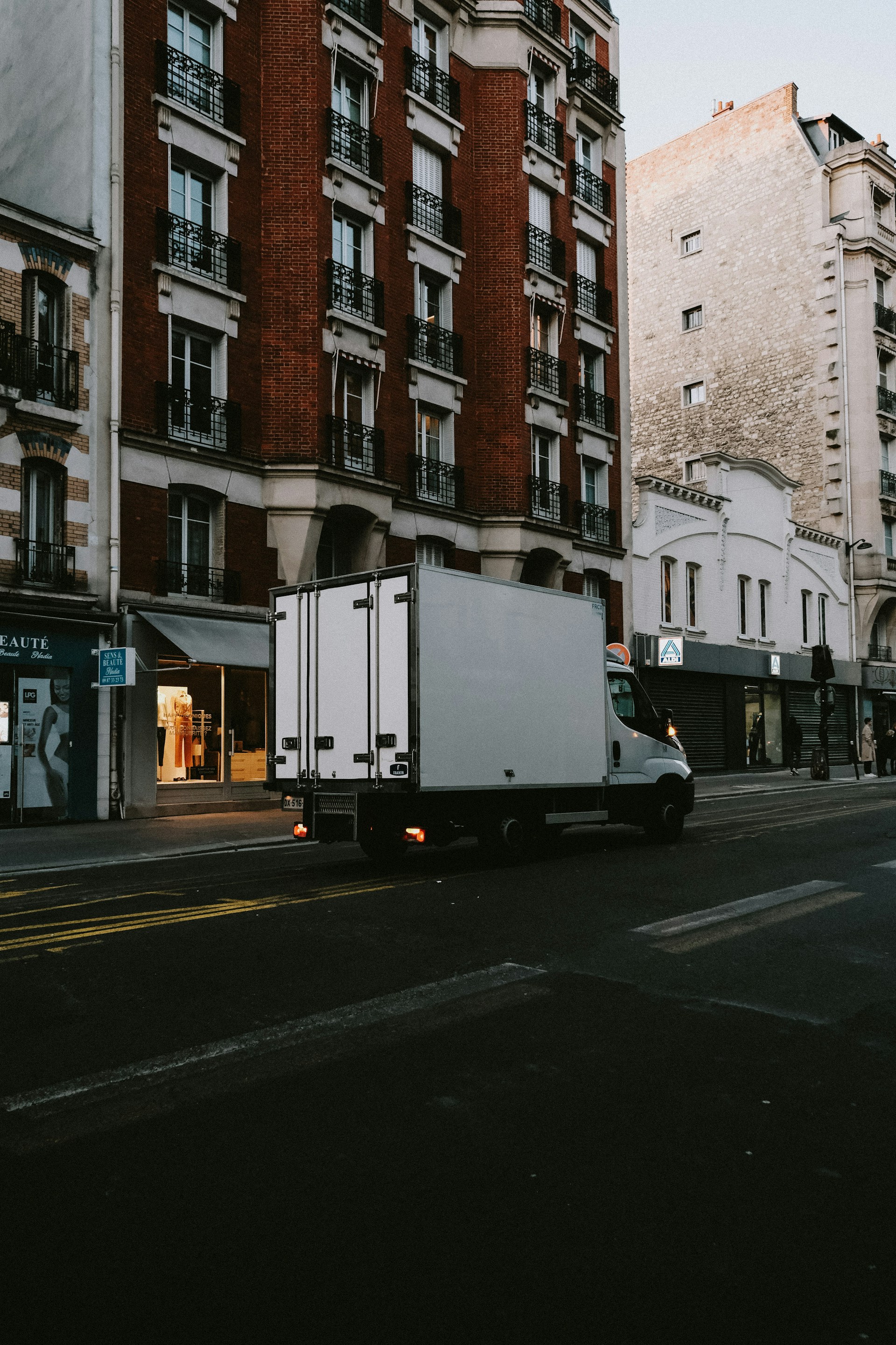 a delivery truck driving down a street next to tall buildings