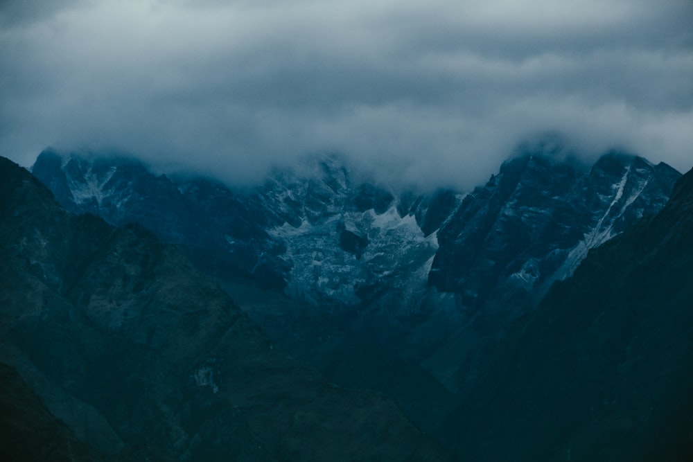 a mountain range covered in snow under a cloudy sky