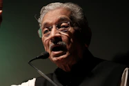 a man with glasses and a mustache speaking into a microphone