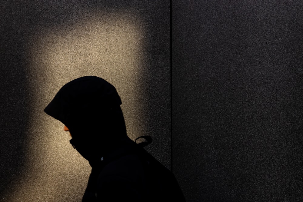 a person standing in the shadows of a wall