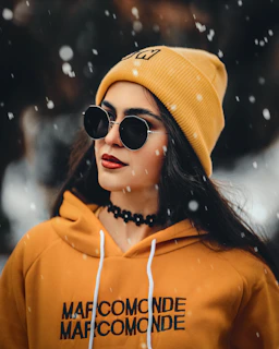a woman wearing a yellow hoodie and black sunglasses