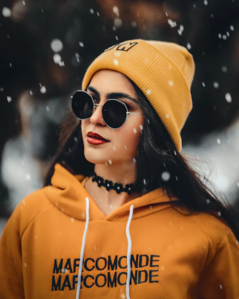 a woman wearing a yellow hoodie and black sunglasses