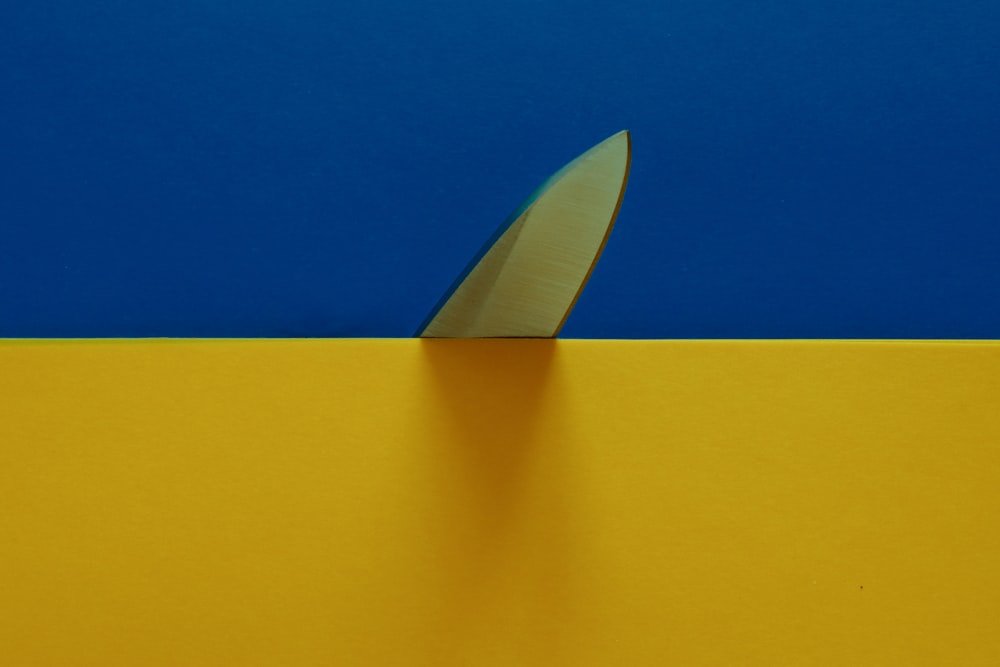 a knife sticking out of the side of a yellow and blue wall